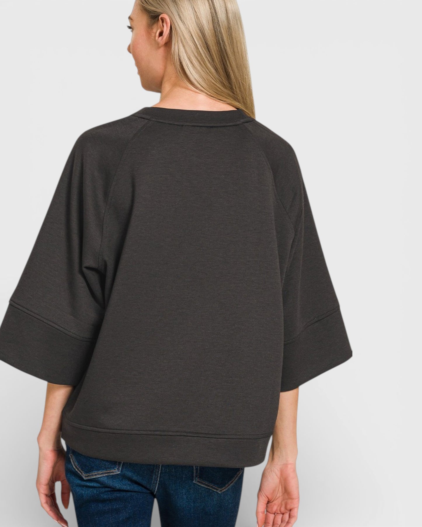 Person wearing a dark gray oversized sweater on a white background
