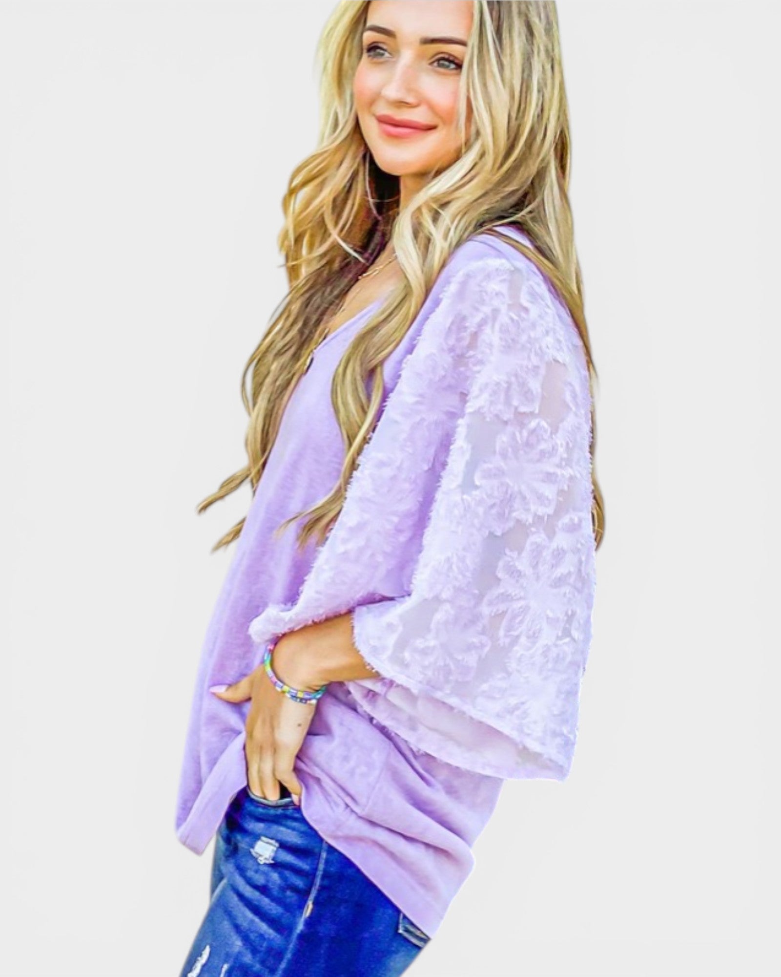 Woman wearing a light purple lace top and blue jeans on a white background