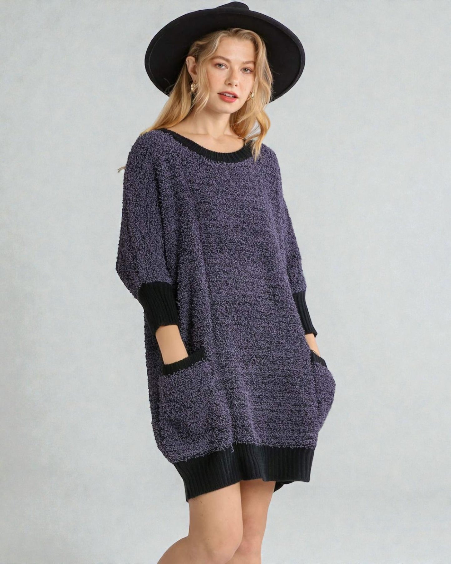 Woman wearing a purple sweater dress with black accents on a gray background