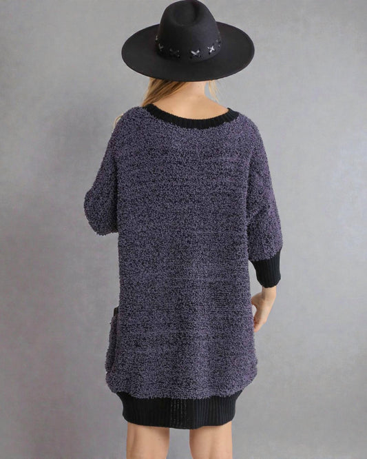 Person wearing a dark textured sweater and black hat on a gray background