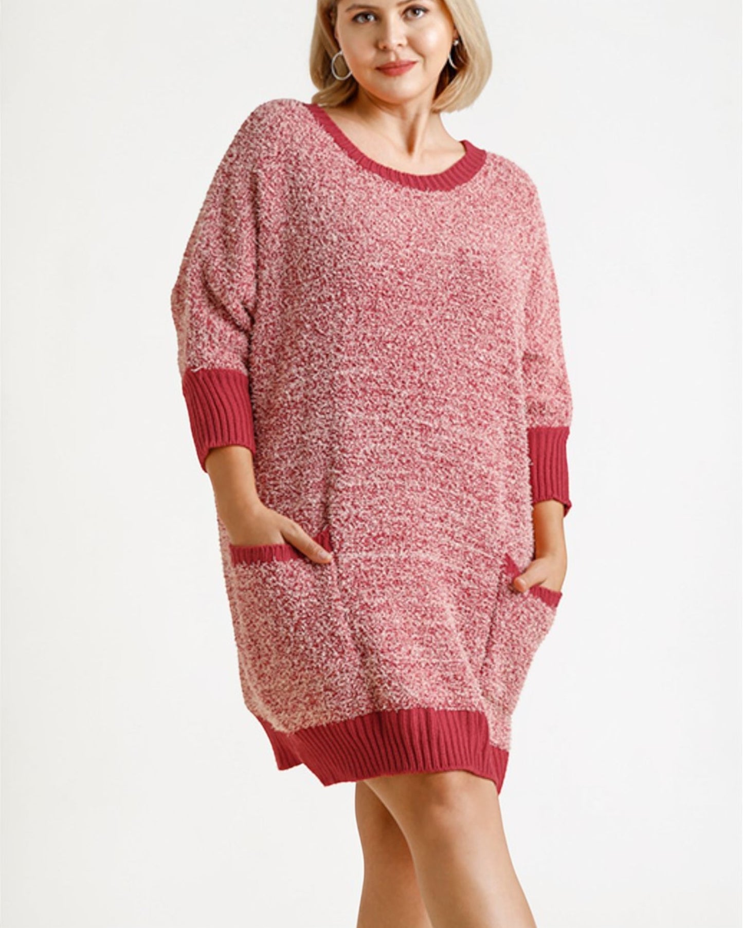 Woman wearing a pink knitted dress with red trim on a white background