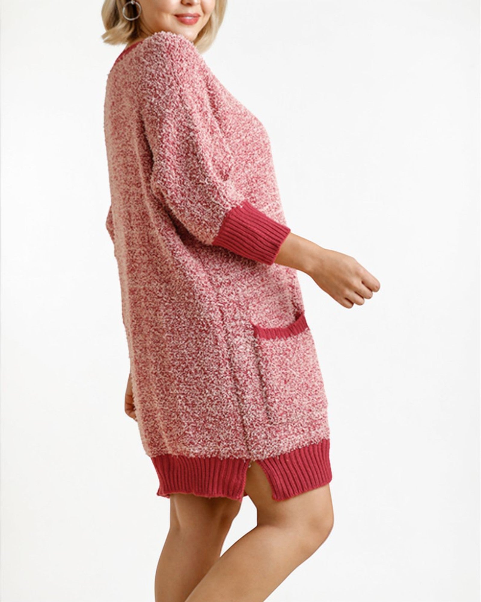 Person wearing a pink knitted cardigan on a white background
