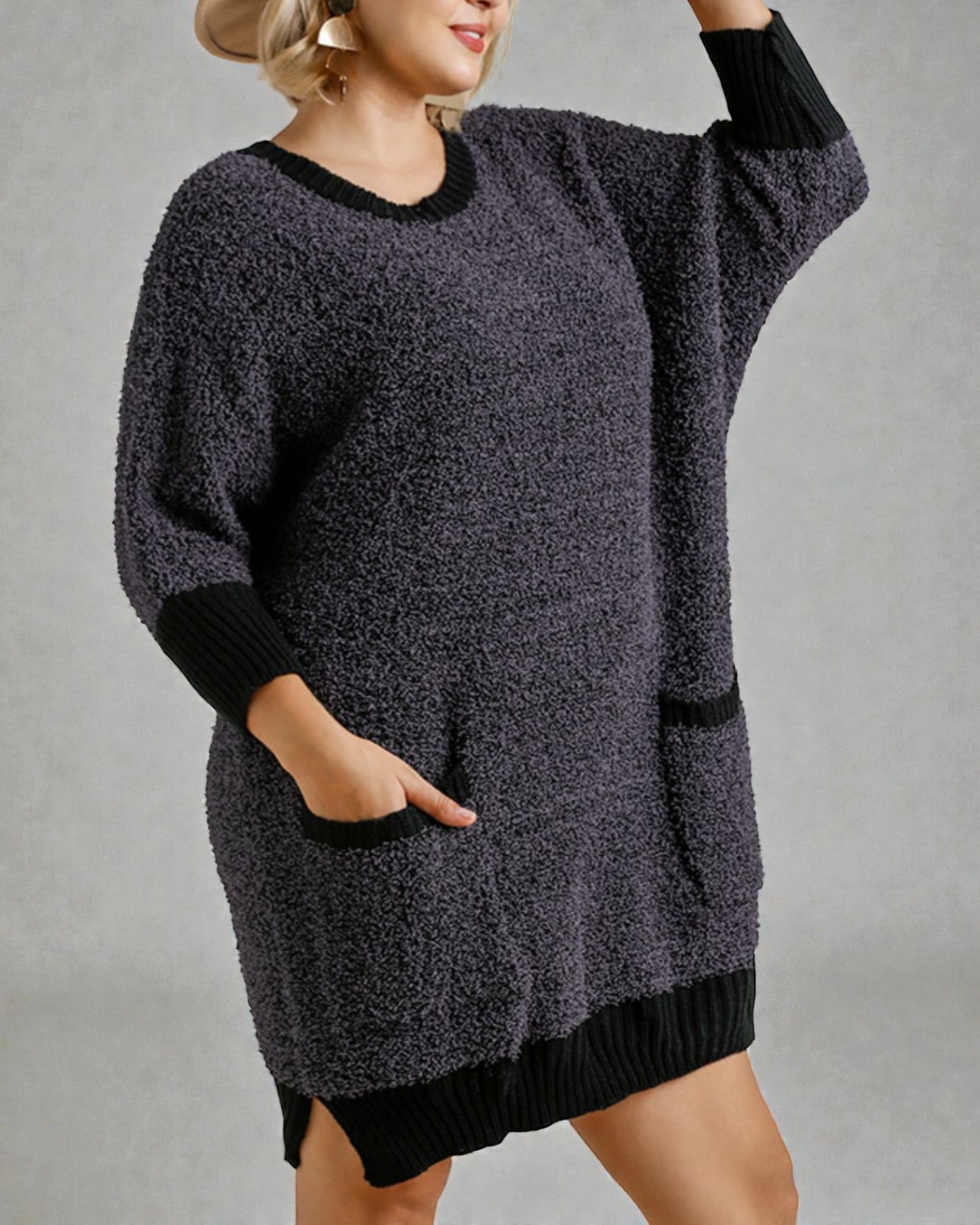 Person wearing a gray sweater dress with black trim on a plain background
