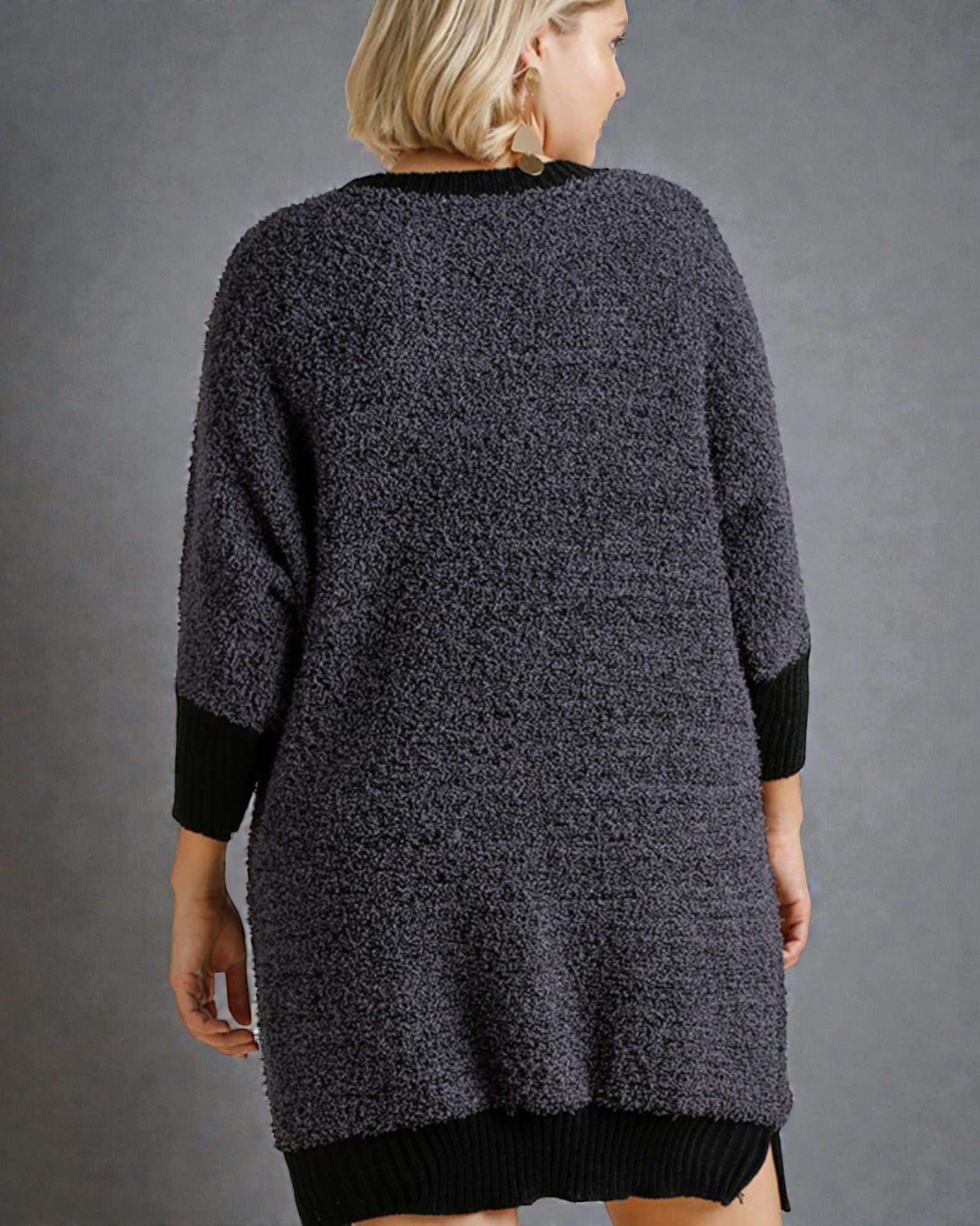 Person wearing a textured gray cardigan against a gray background