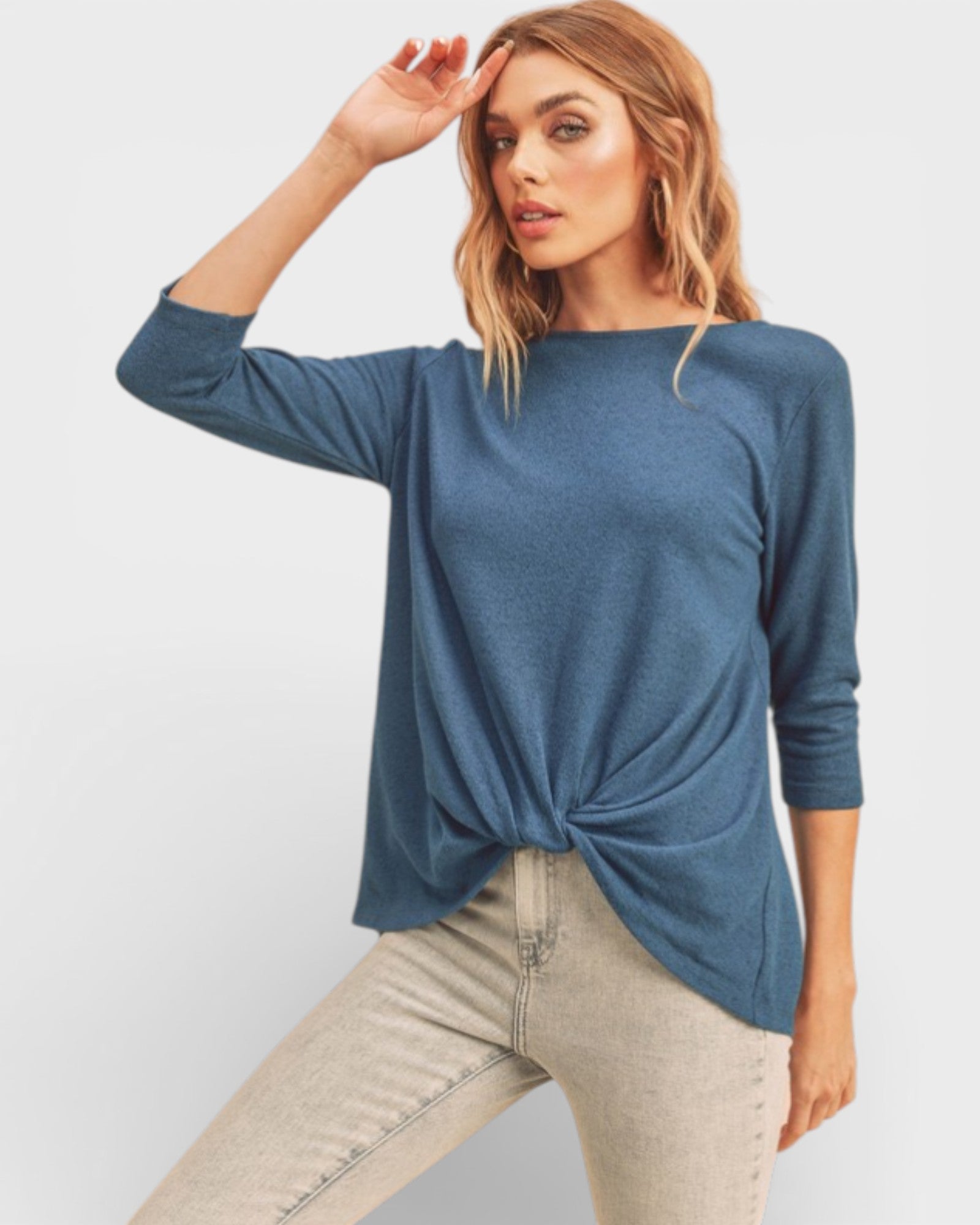 Woman wearing a blue long-sleeve top with a knot detail on a white background
