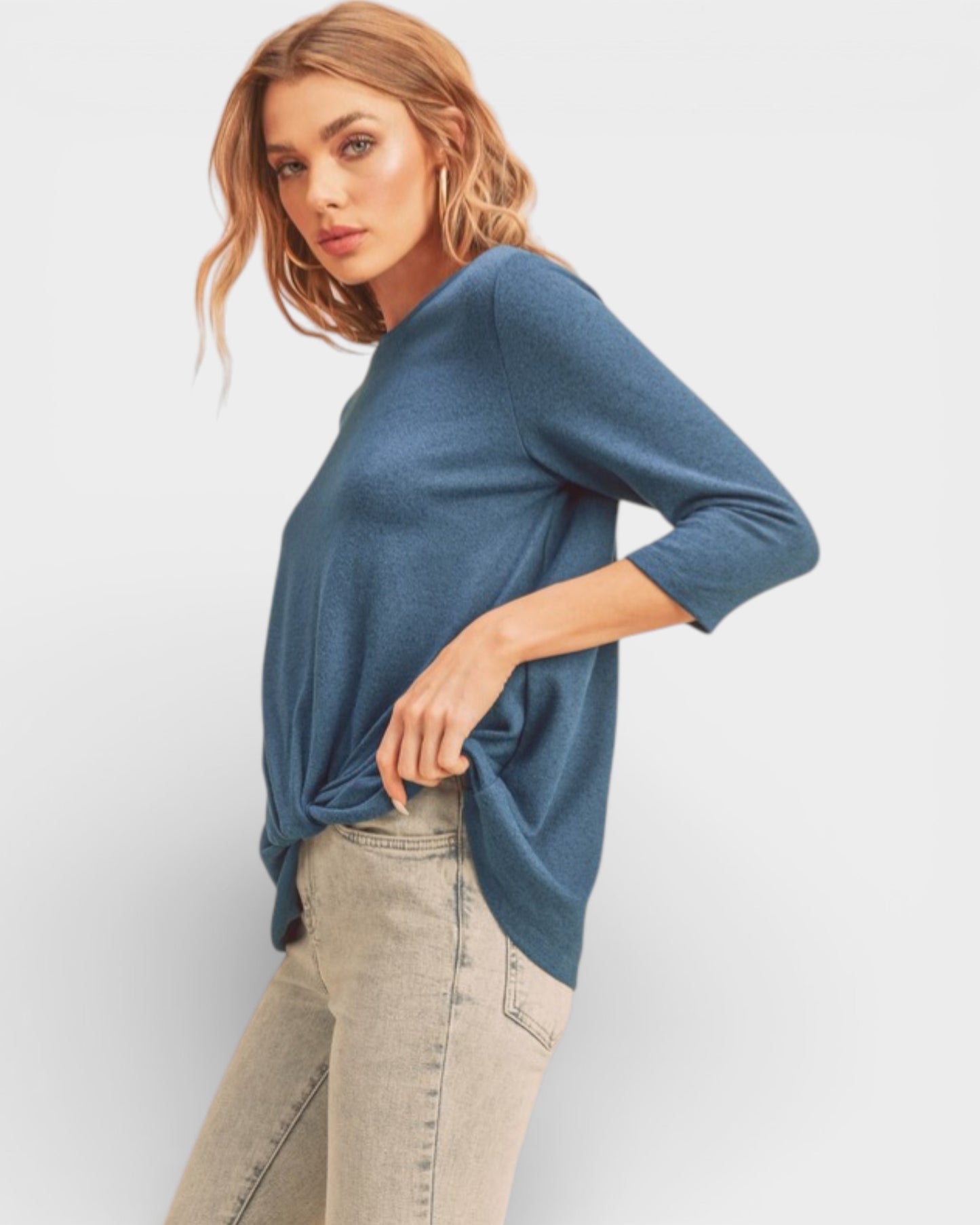 Woman wearing a blue sweater and beige pants on a white background