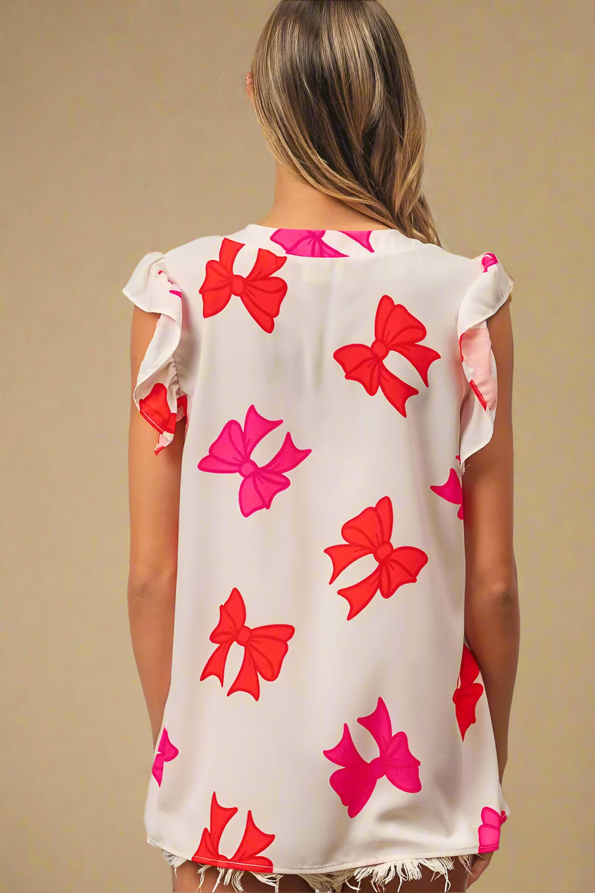 Woman wearing a sleeveless top with red and pink bow patterns on a white background