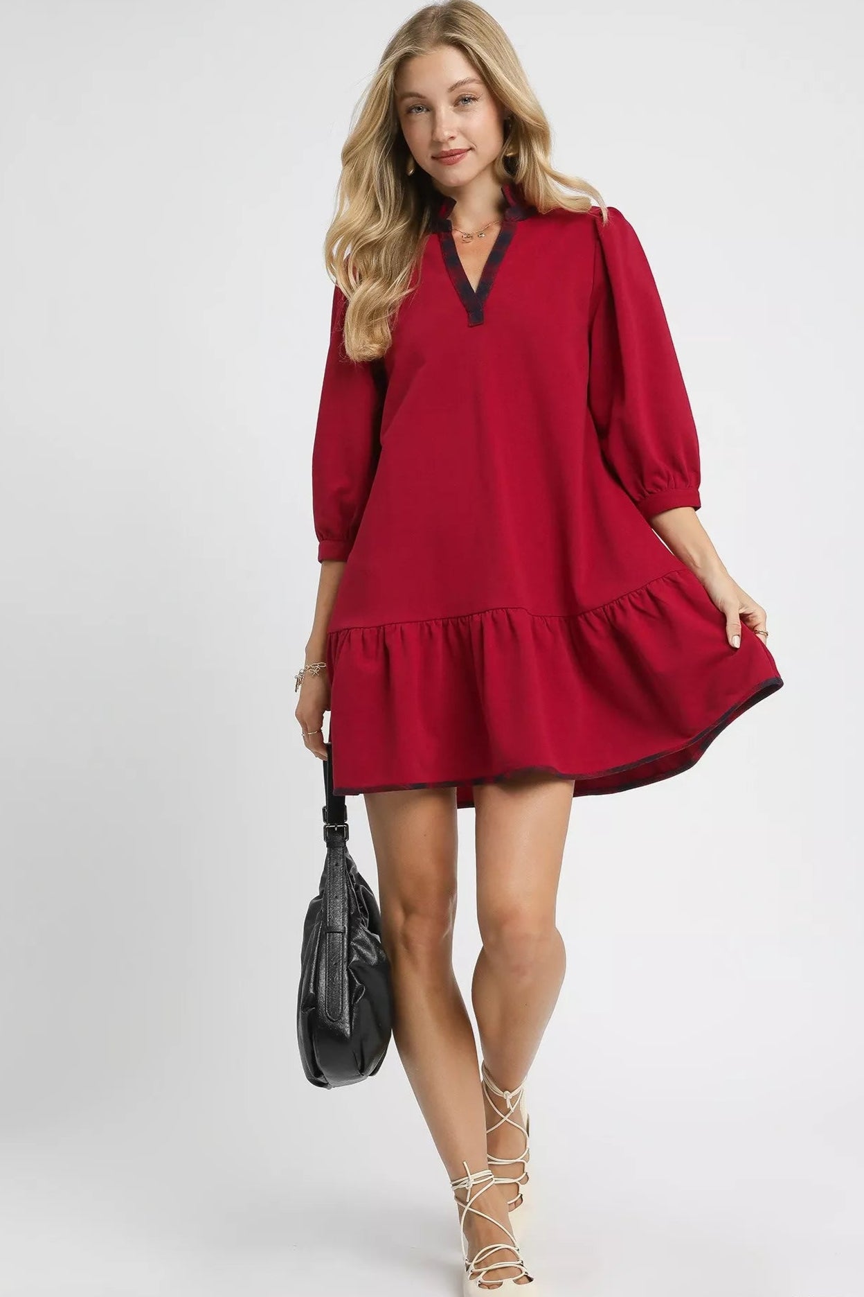 Woman wearing a red dress with a black collar on a white background