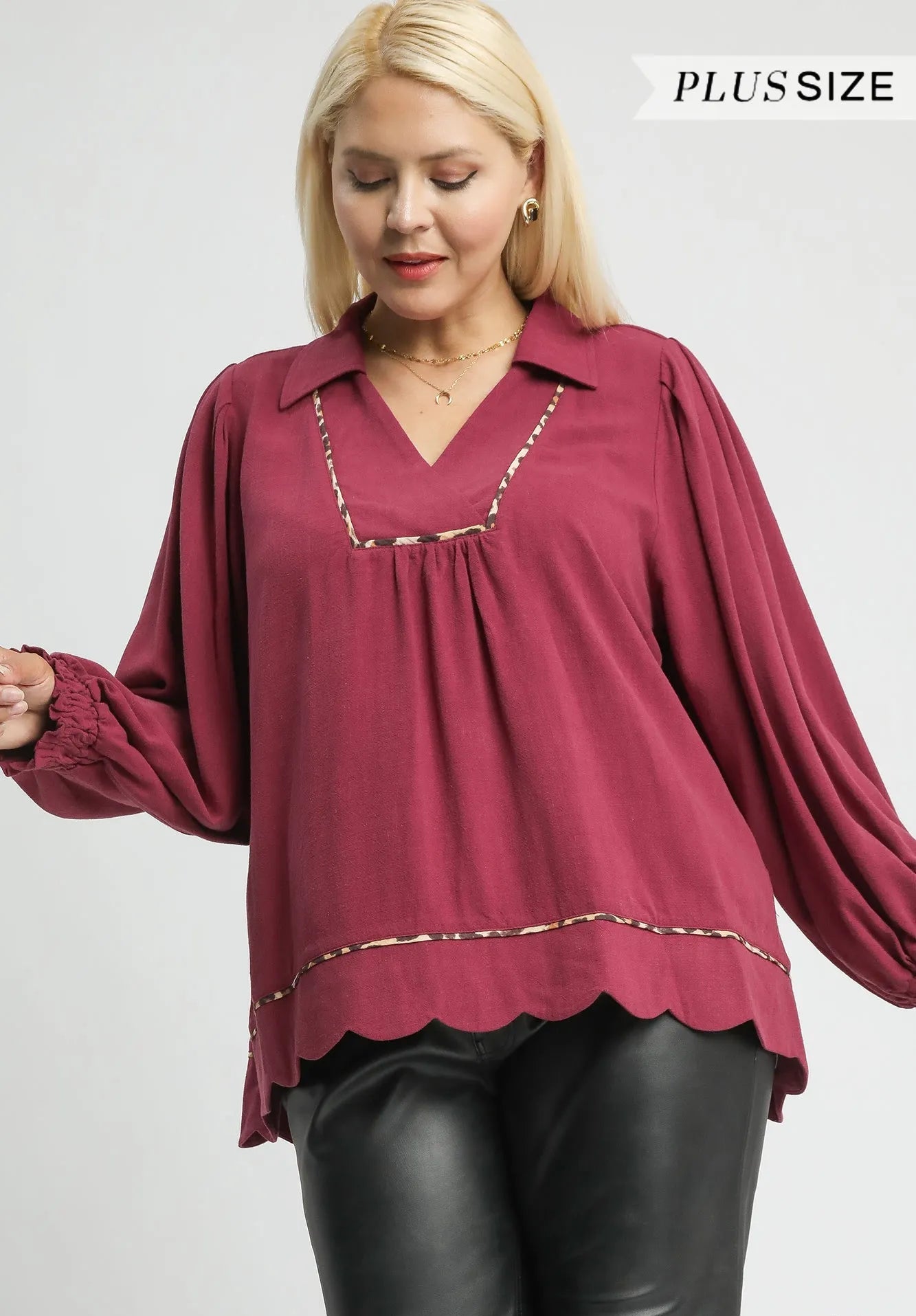 Woman wearing a maroon blouse with long sleeves on a white background