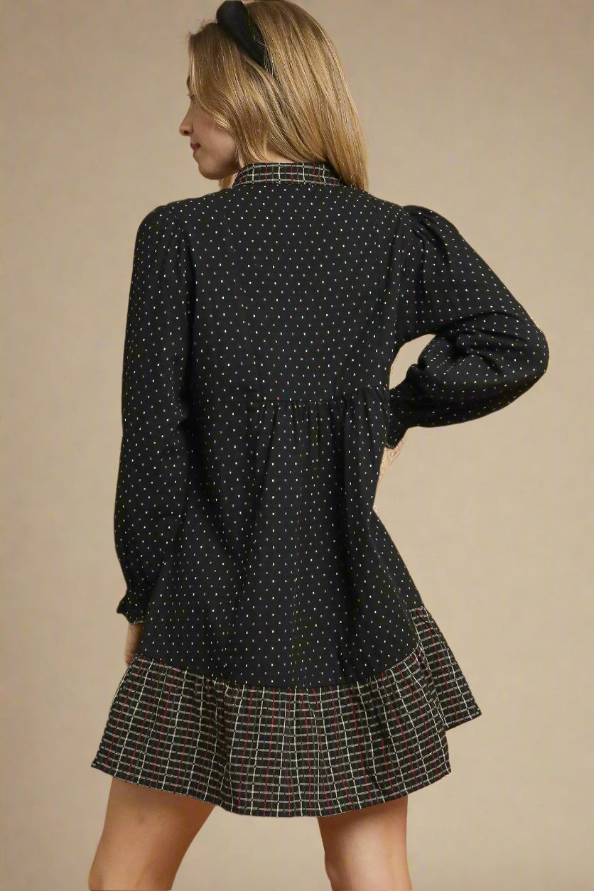 Woman wearing a black polka dot dress with plaid trim on a beige background