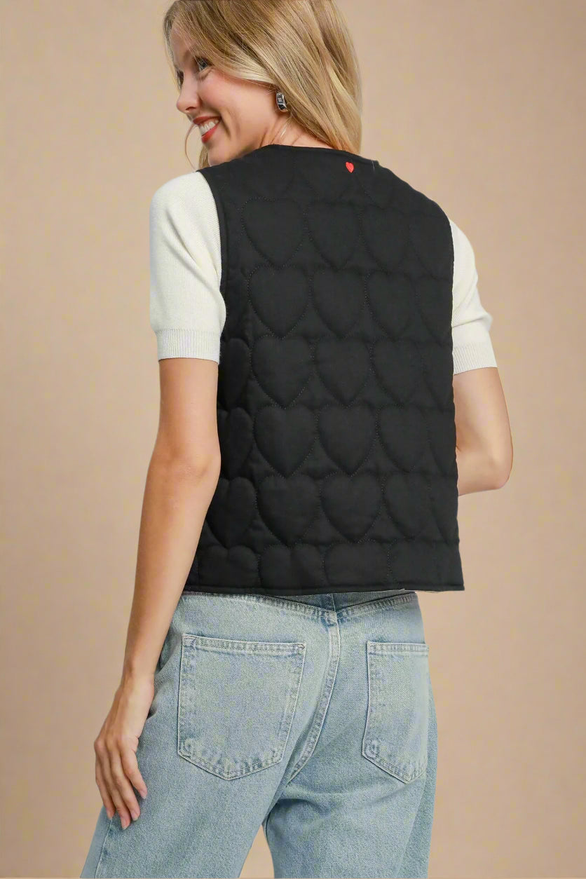Woman wearing a black quilted vest on a beige background