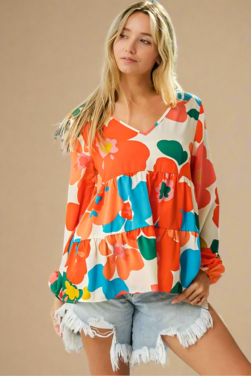 Woman wearing a colorful floral blouse and denim shorts