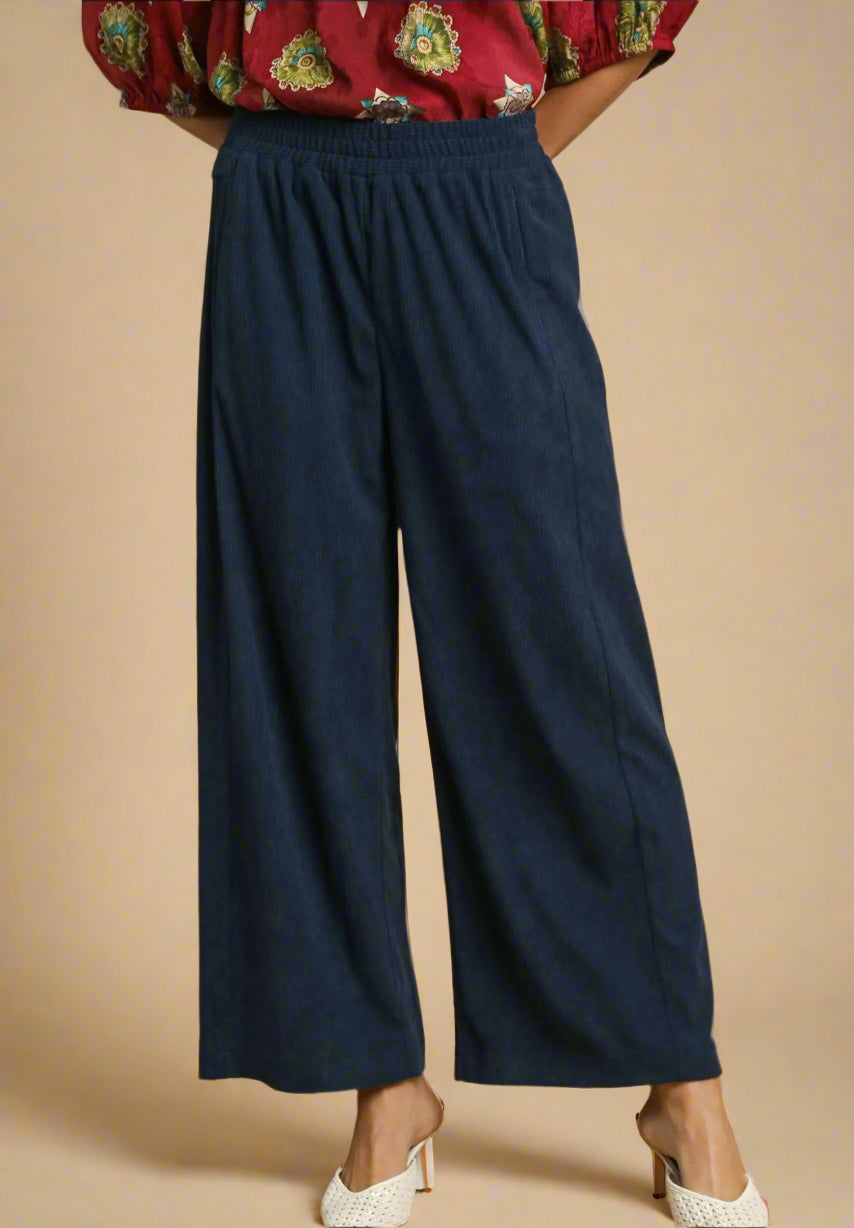 Navy blue wide-leg pants worn with a red floral top on a beige background