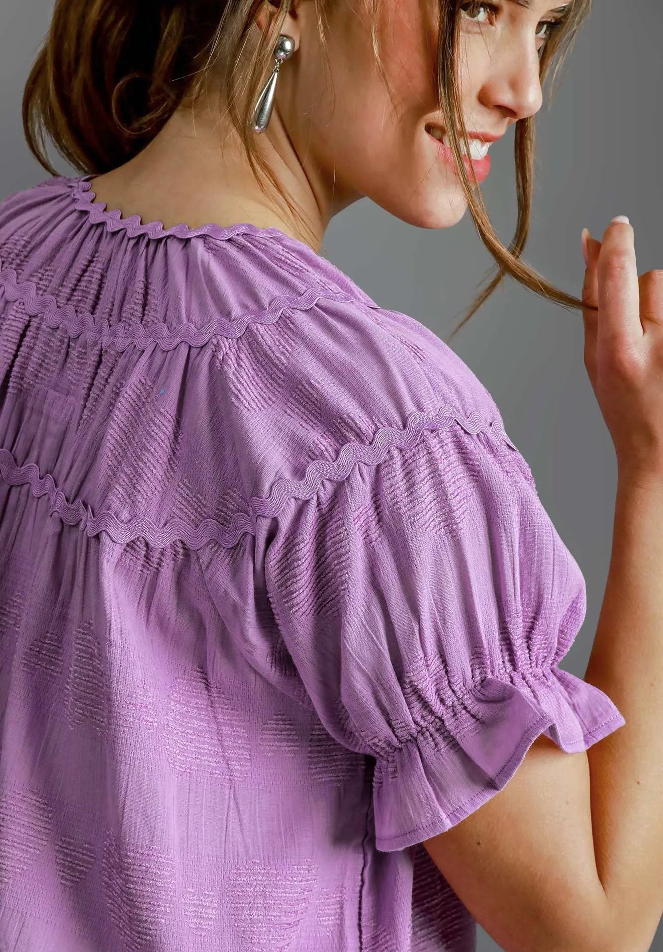 Woman wearing a lavender blouse with a gray background