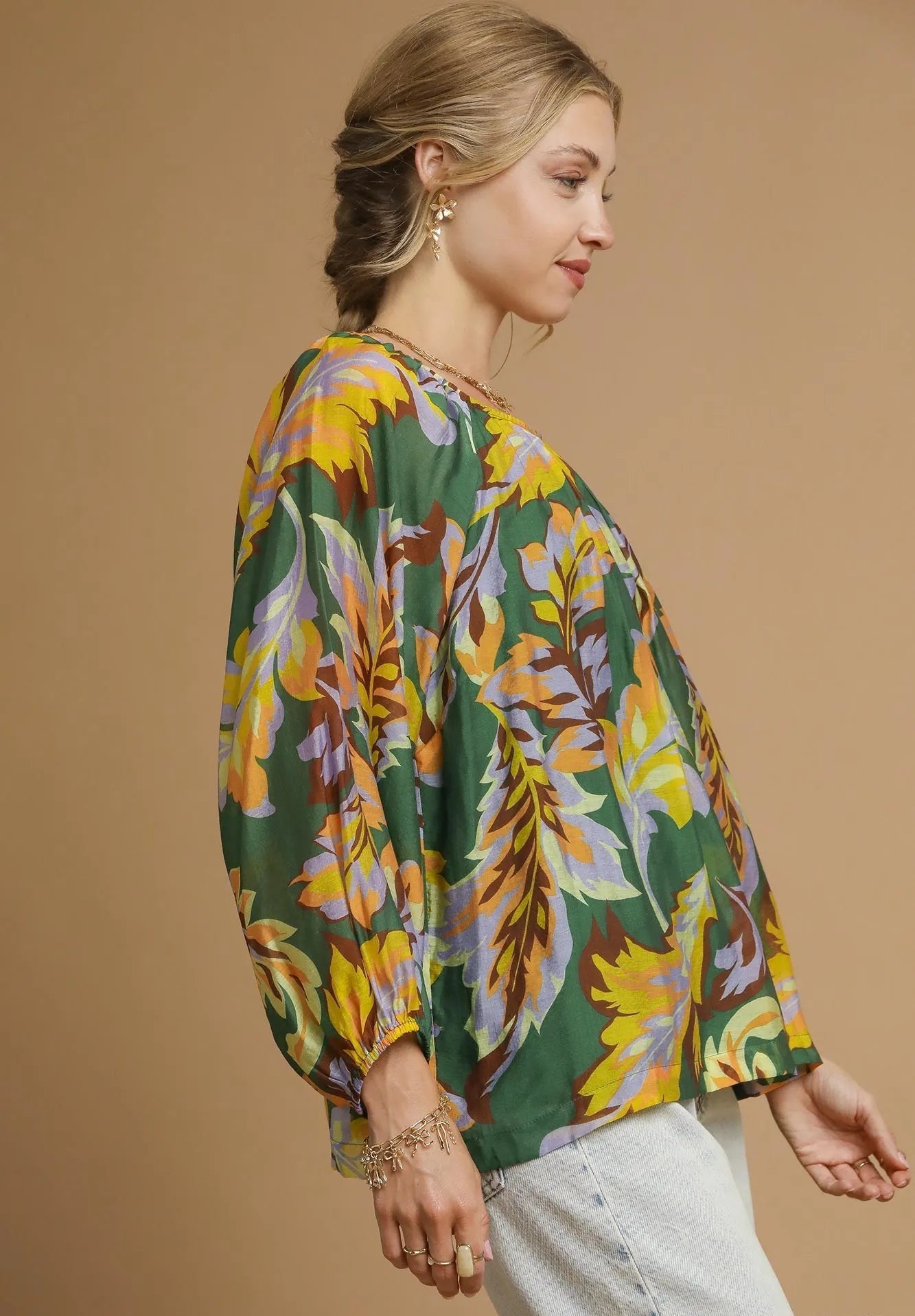 Woman wearing a colorful floral blouse with a beige background