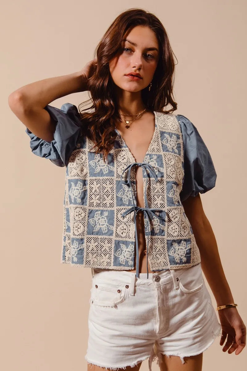 Woman wearing a patterned top and white shorts against a beige background