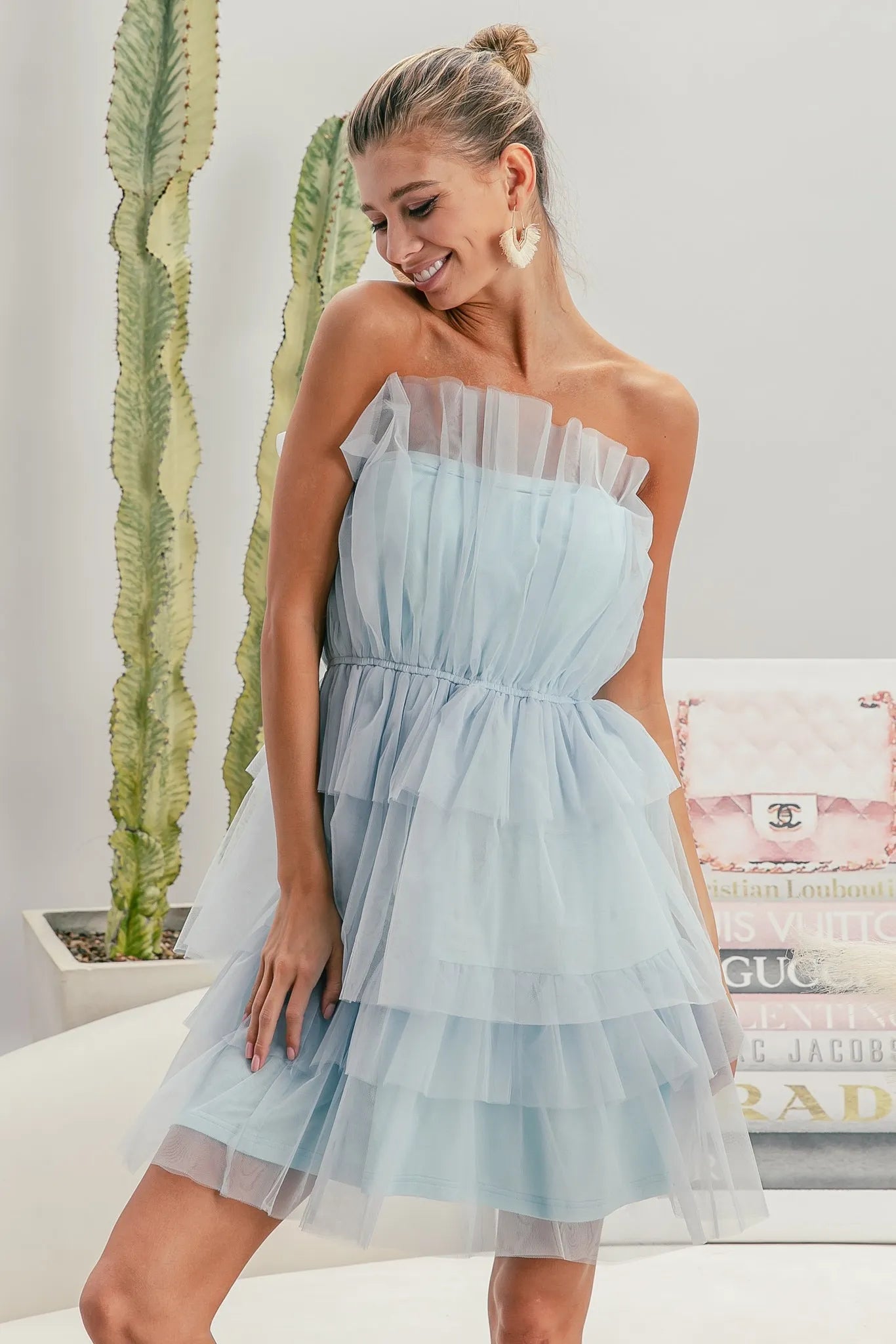 Woman wearing a light blue strapless dress with a blurred indoor background