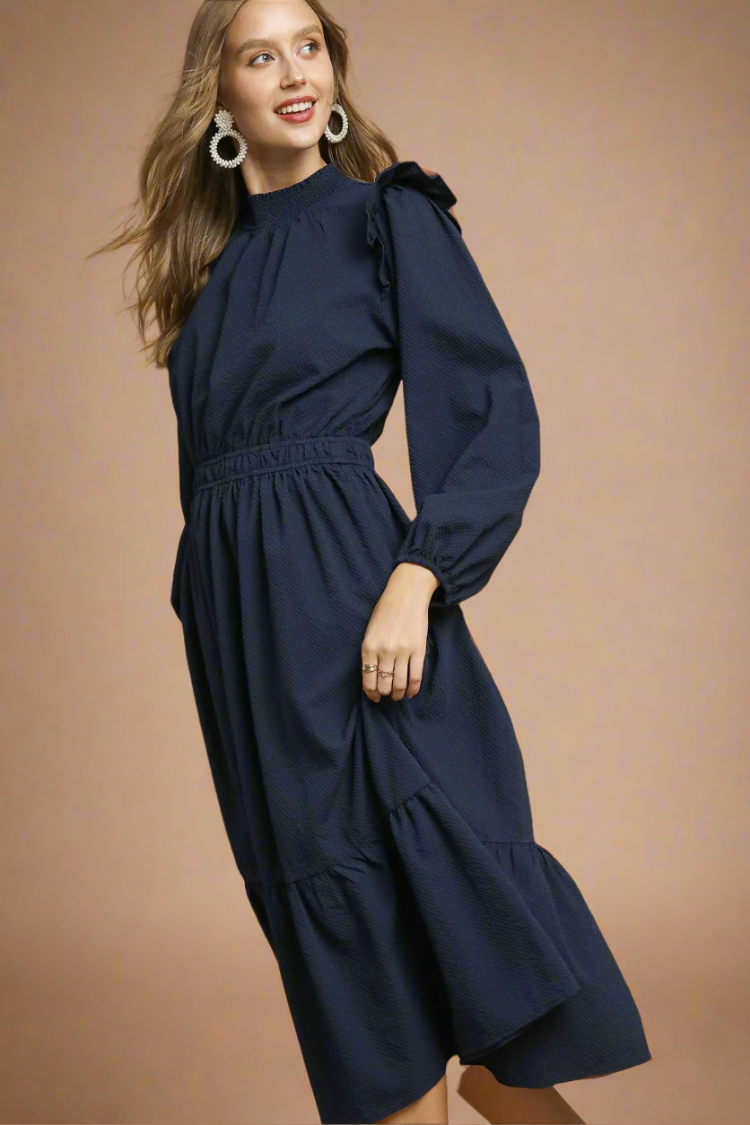 Woman wearing a navy dress against a brown background