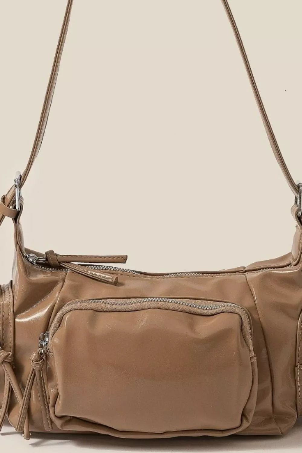 Brown leather handbag with a shoulder strap on a beige background