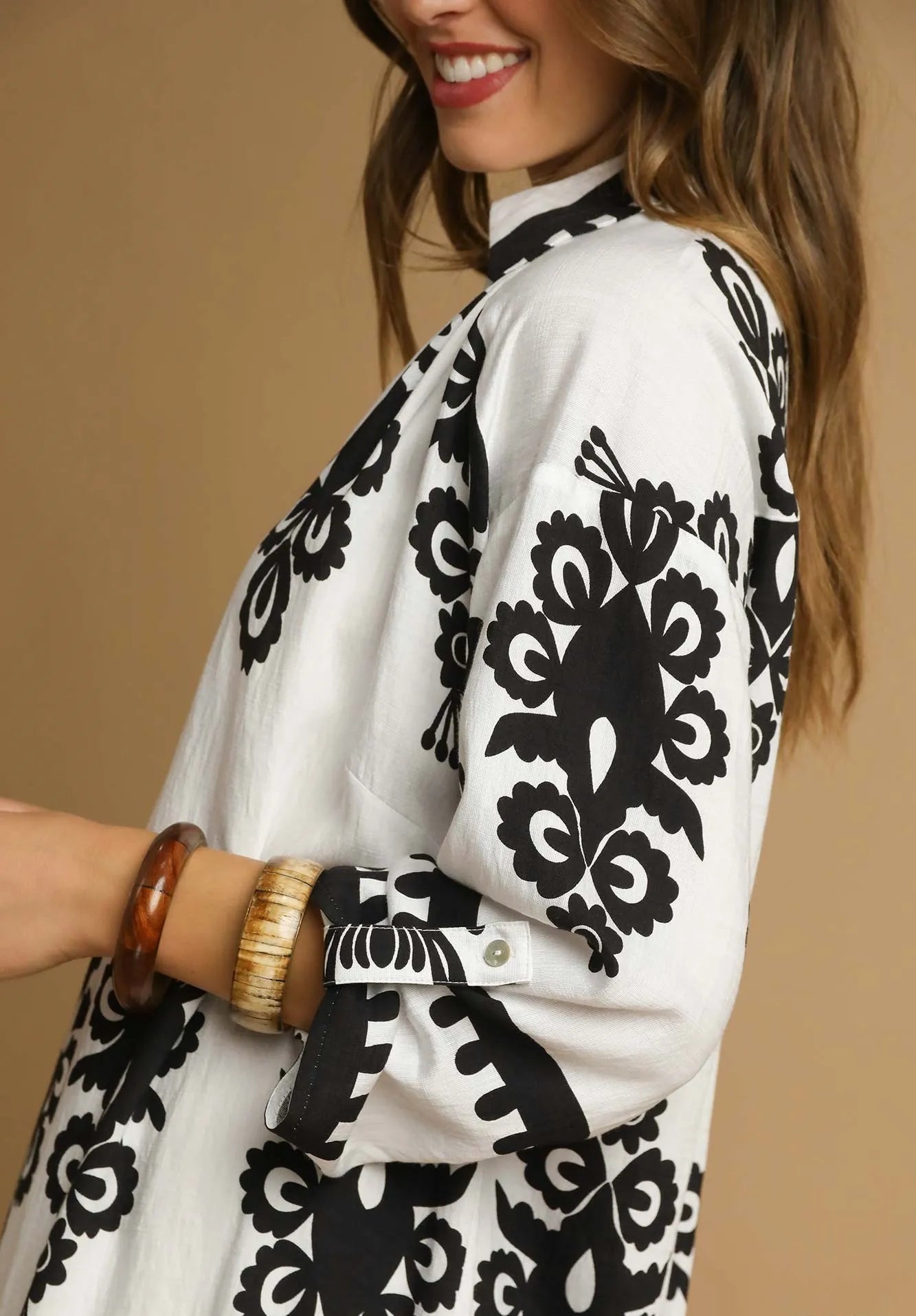 Woman wearing a white dress with black floral patterns on a beige background