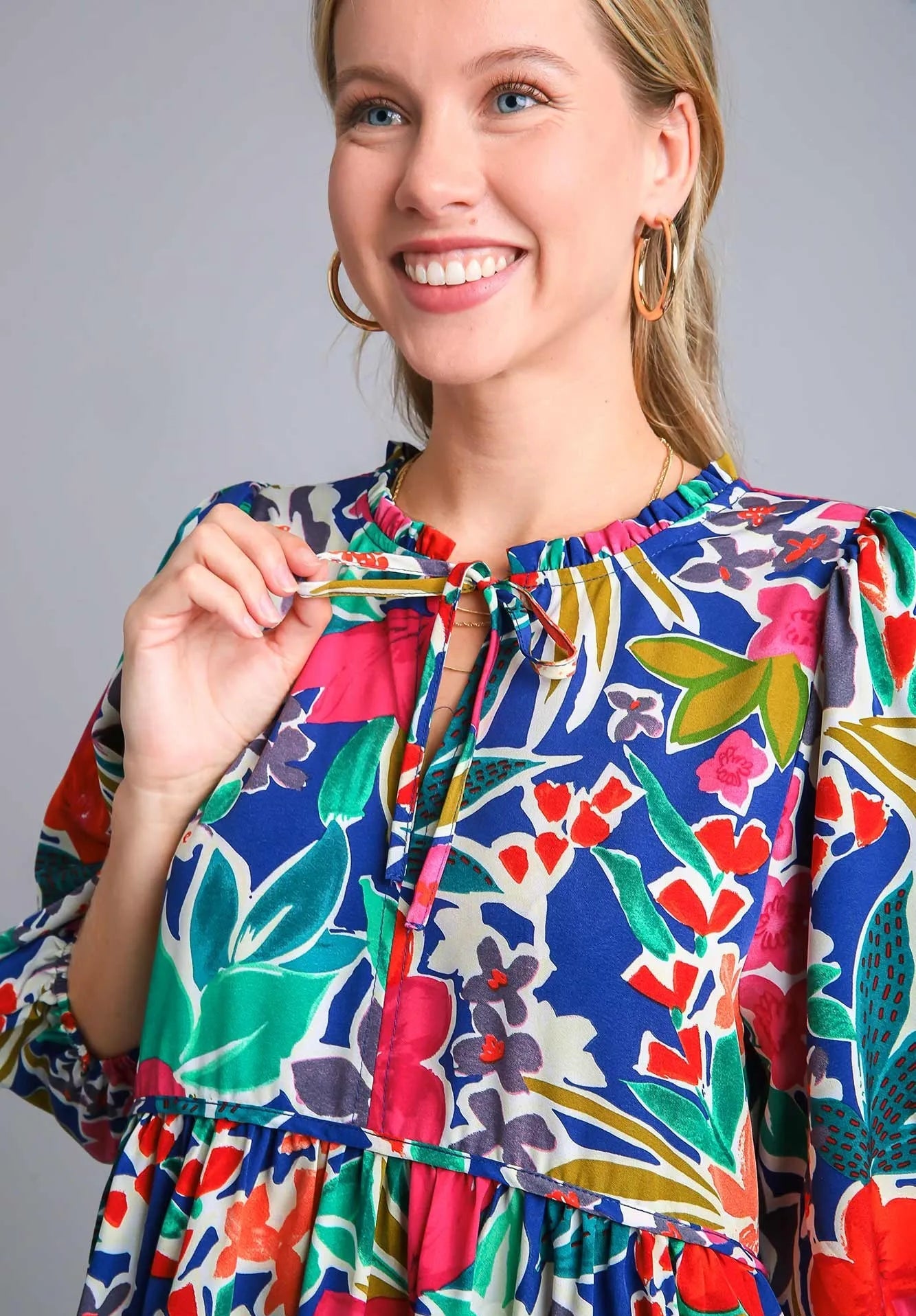 Woman wearing a colorful floral dress against a gray background