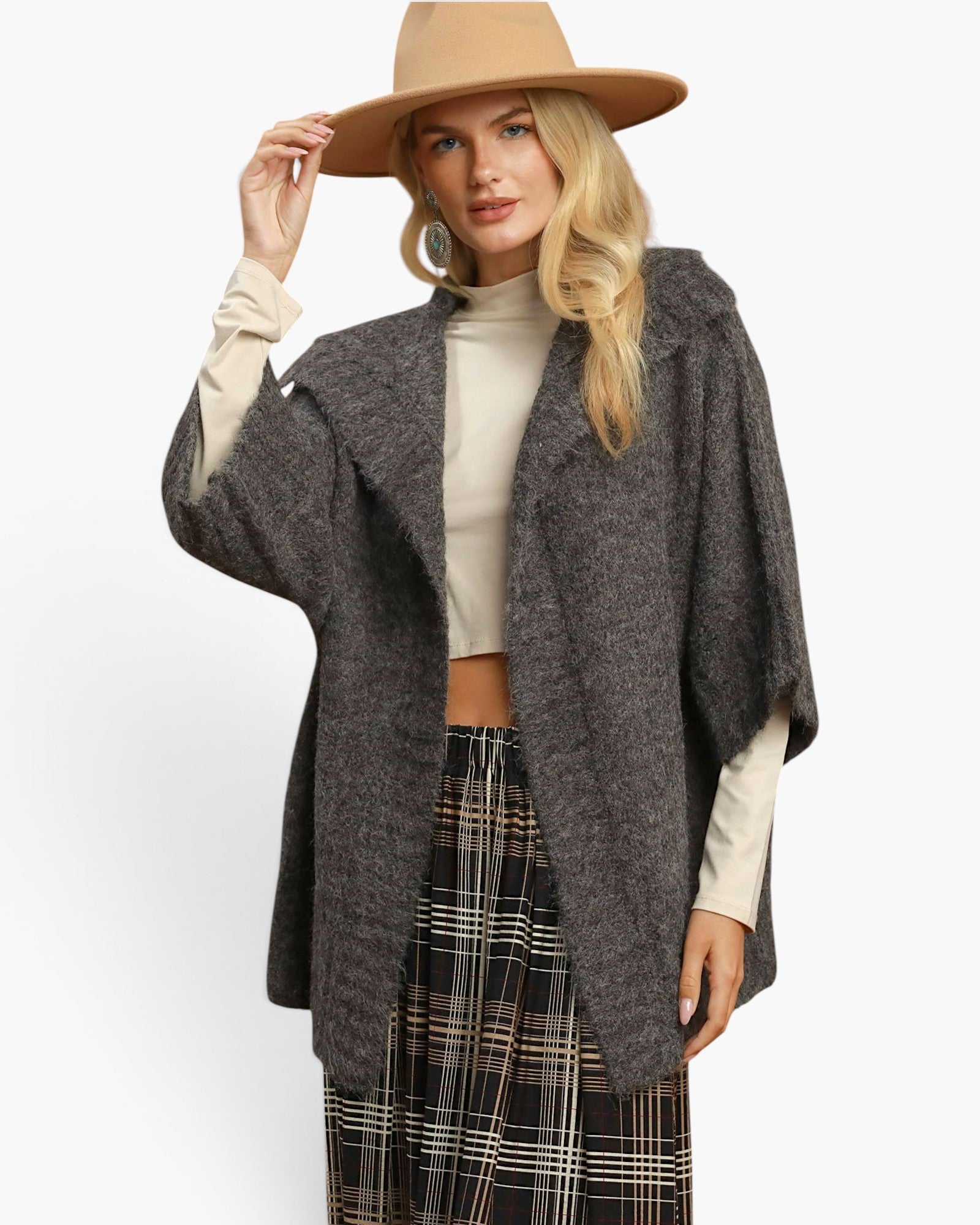 A woman modeling a dark gray textured open-front poncho-style cardigan over a cream mock-neck top and a black plaid skirt, wearing a tan wide-brim hat against a plain white studio background.