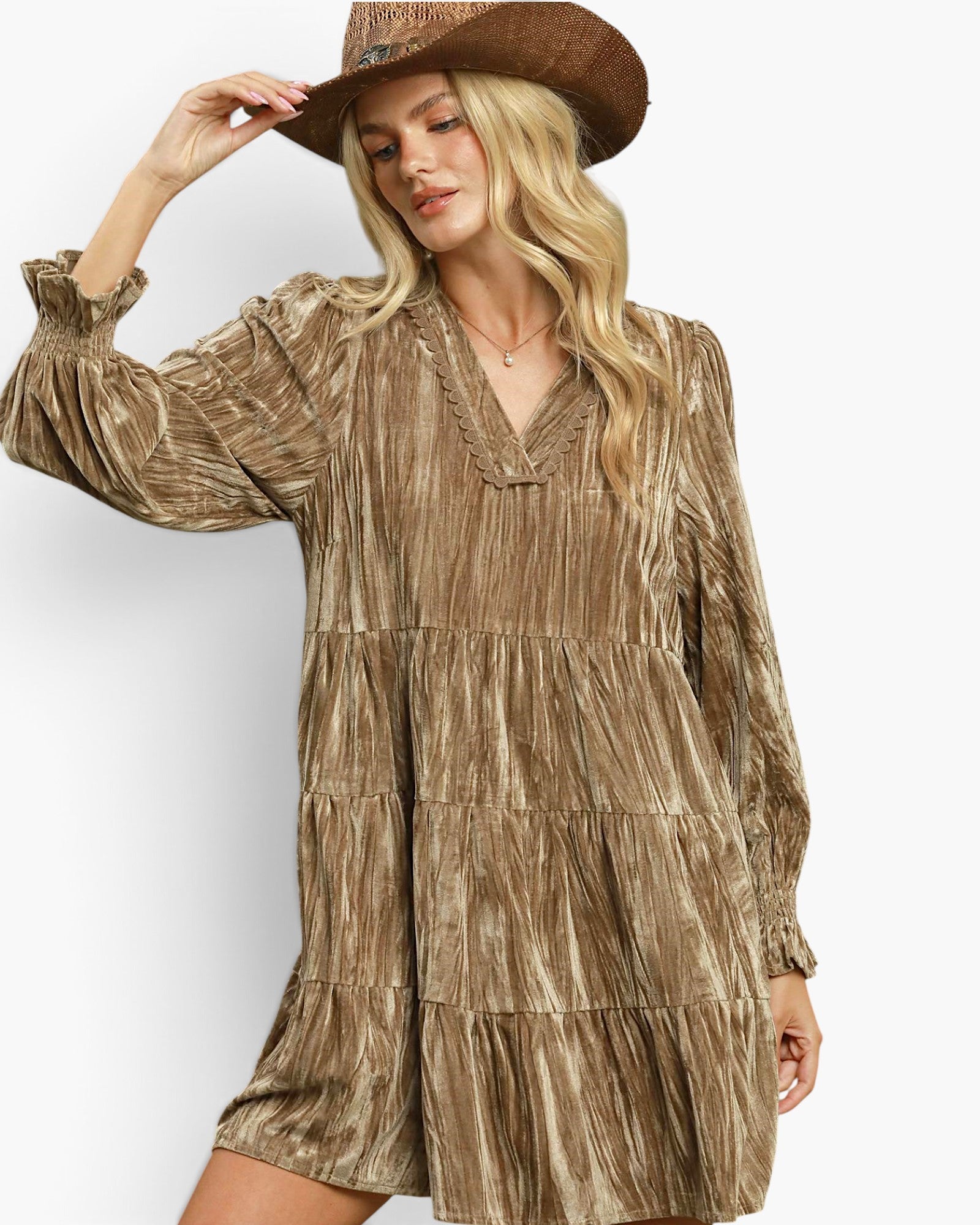 A woman wearing a bronze metallic-textured tiered dress with long sleeves and a matching brown cowboy hat, posing against a plain white studio background.