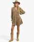 A woman modeling a tiered, long-sleeve mini dress in a textured metallic bronze-gold fabric, styled with a brown cowboy hat and tan cowboy boots against a light gray studio background.
