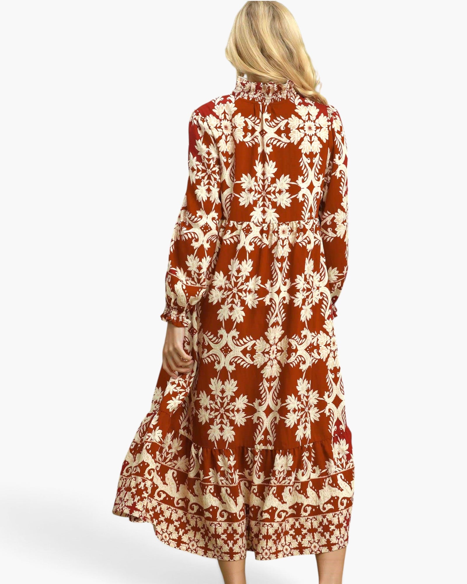 A woman shown from the back wearing a long-sleeve midi dress with a rust-orange and cream floral snowflake pattern, set against a plain white studio background.