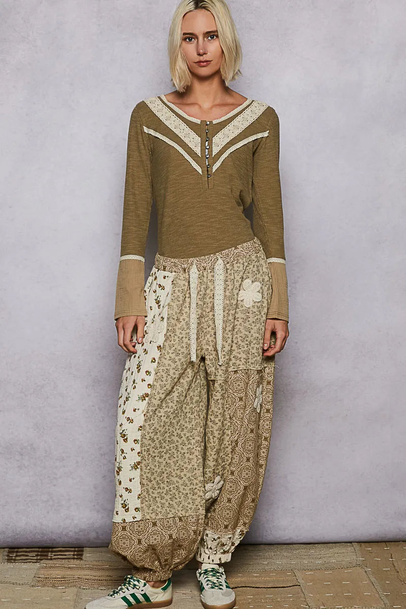 Woman wearing a green top and patterned pants against a plain background