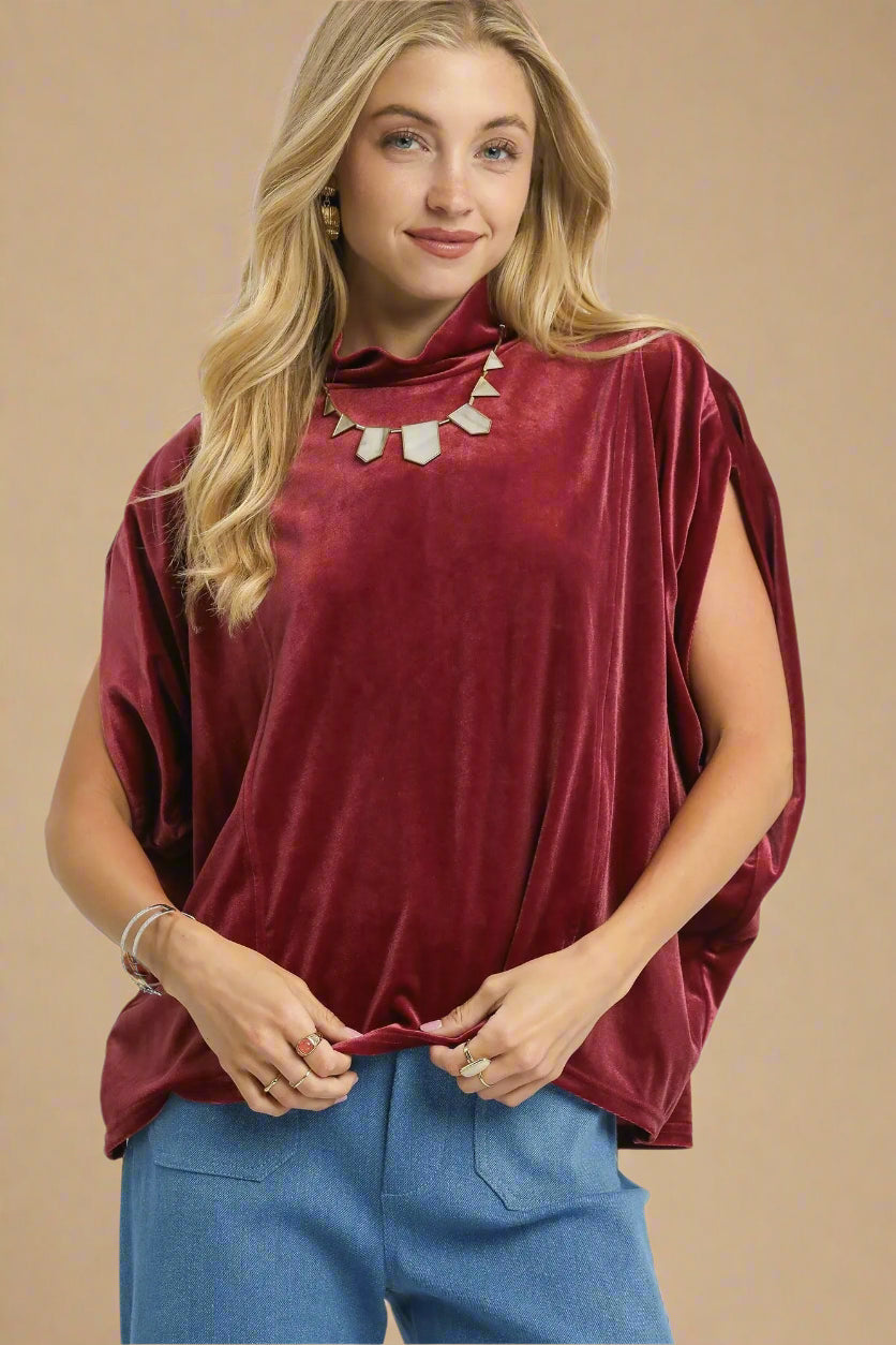 Woman wearing a burgundy top and blue pants on a beige background