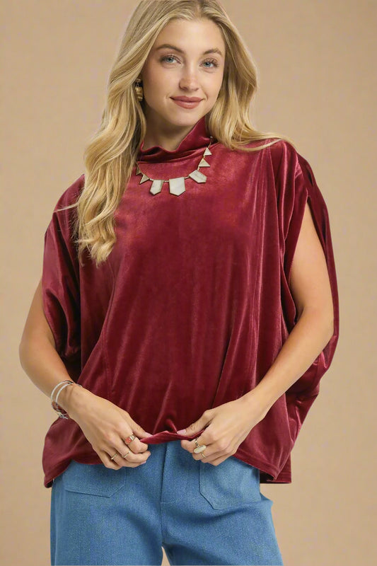 Woman wearing a burgundy top and blue pants on a beige background