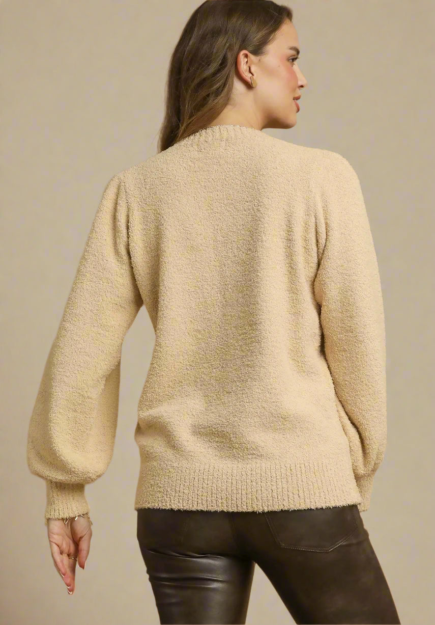 Woman wearing a beige sweater against a brown background