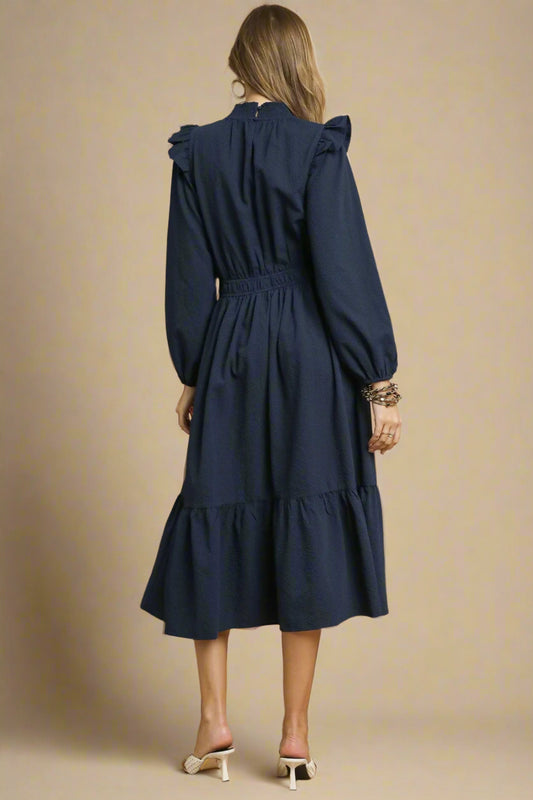 Woman wearing a navy dress against a beige background