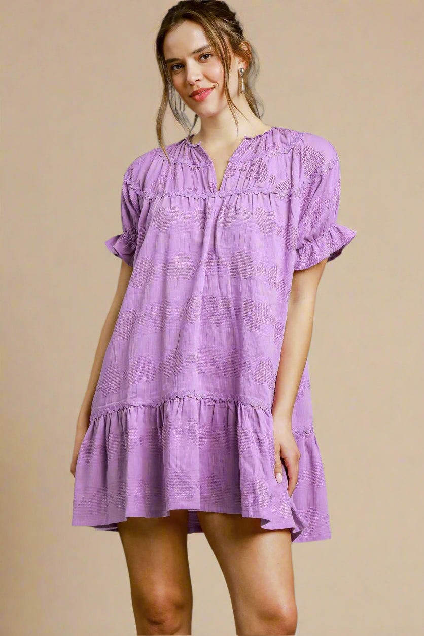 Woman wearing a lavender dress against a beige background