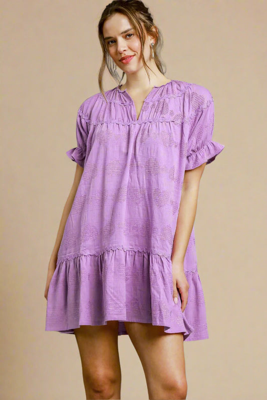 Woman wearing a lavender dress against a beige background
