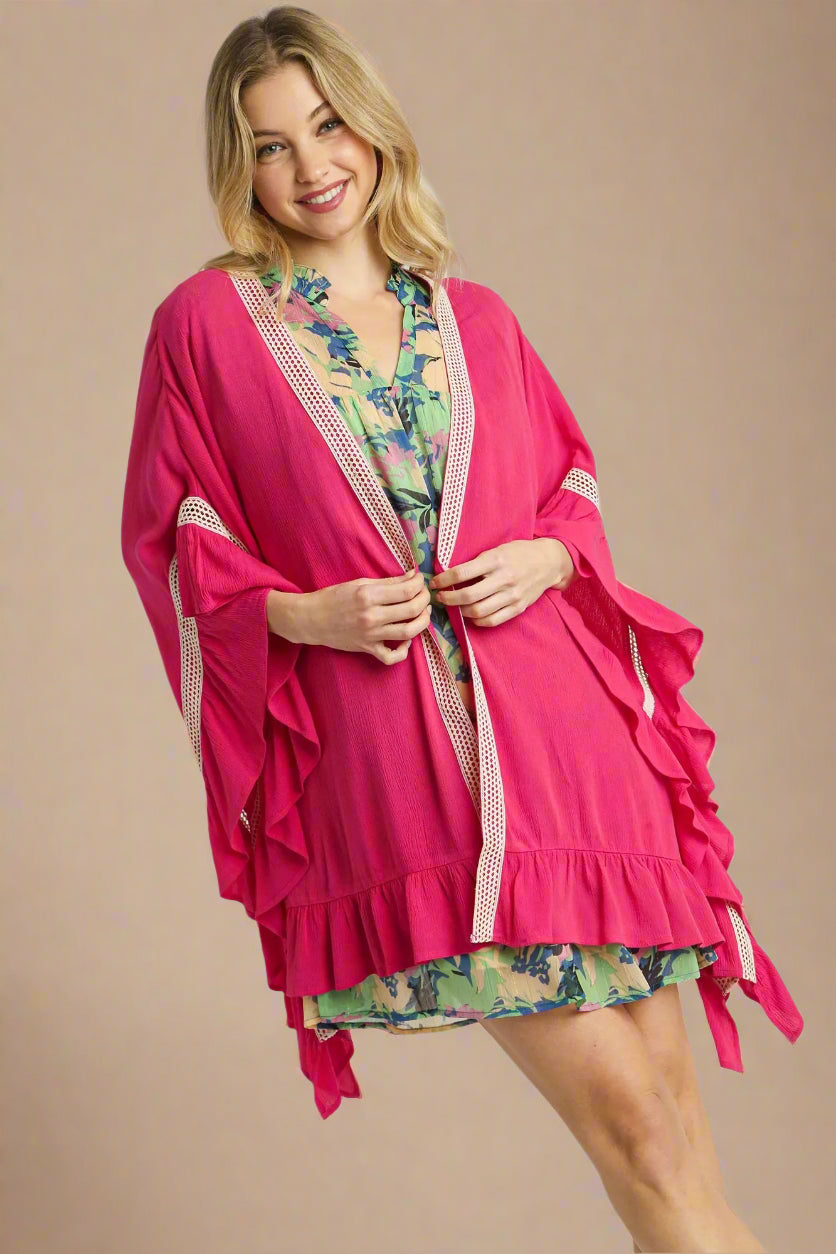 Woman wearing a pink cover-up with floral dress underneath on a white background