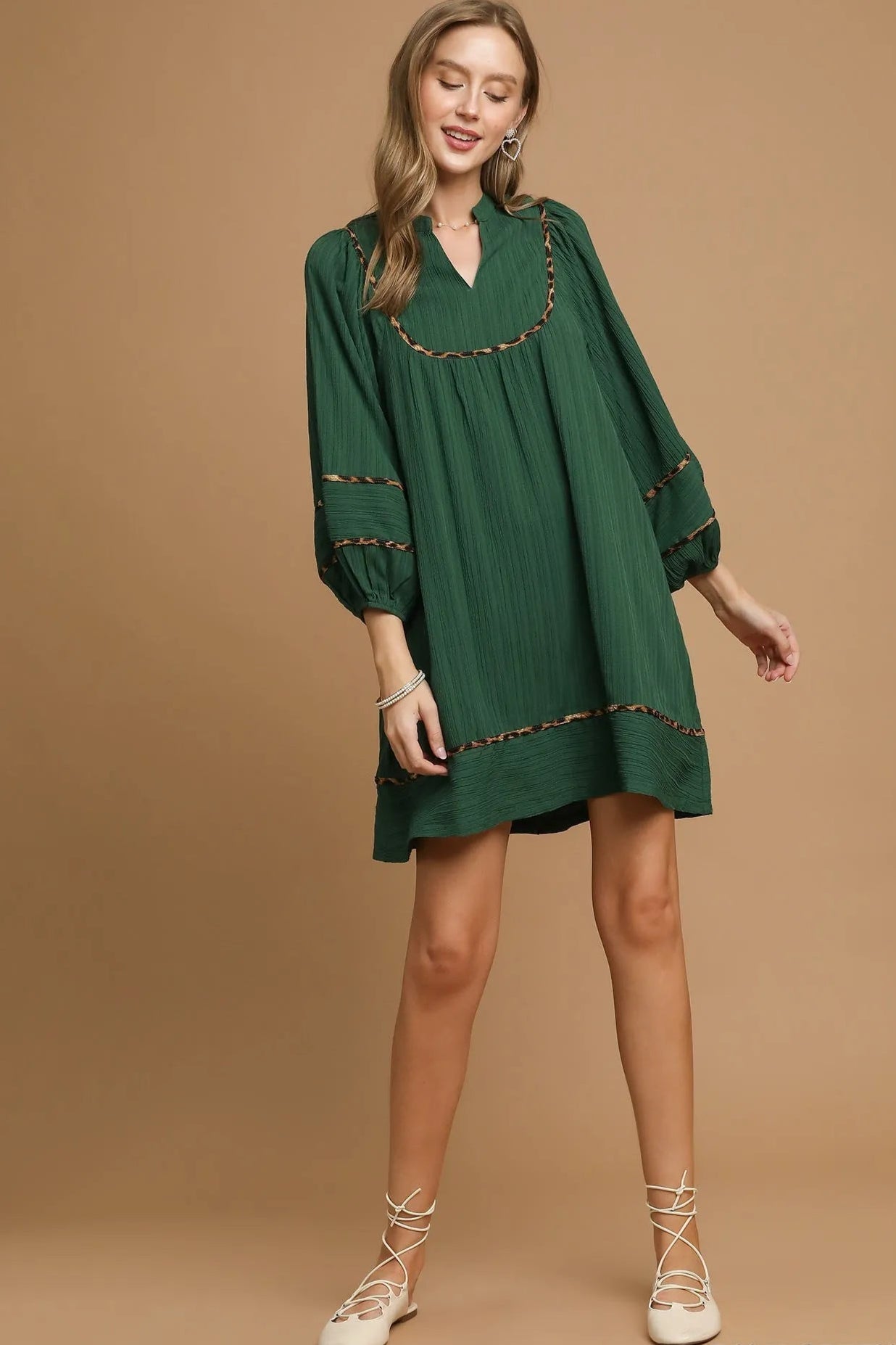 Woman wearing a green dress with lace details on a beige background