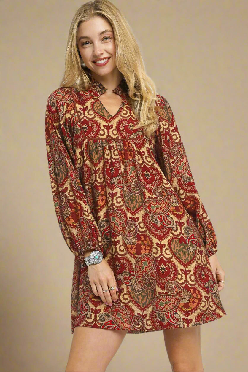 Woman wearing a patterned dress with long sleeves on a beige background