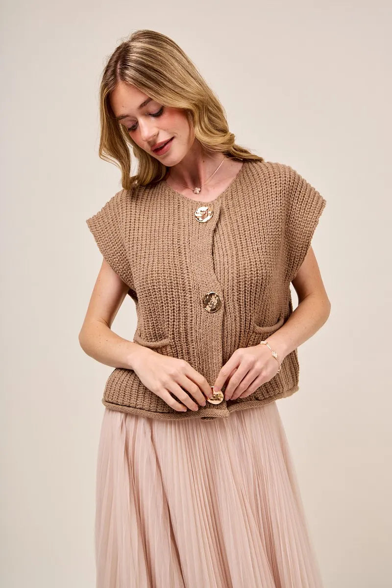 Woman wearing a brown knitted vest with buttons on a plain background