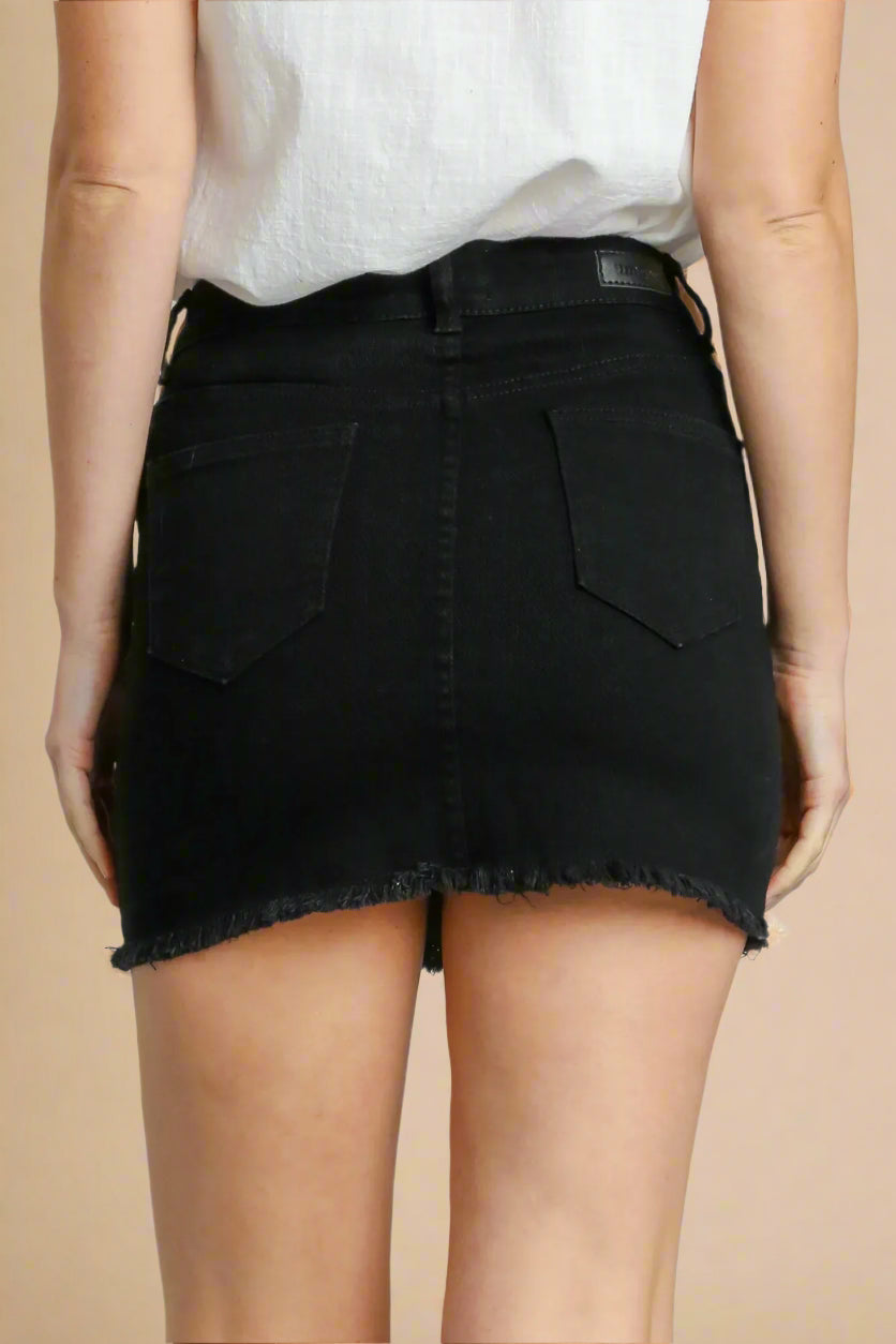 Black denim skirt worn by a person on a beige background