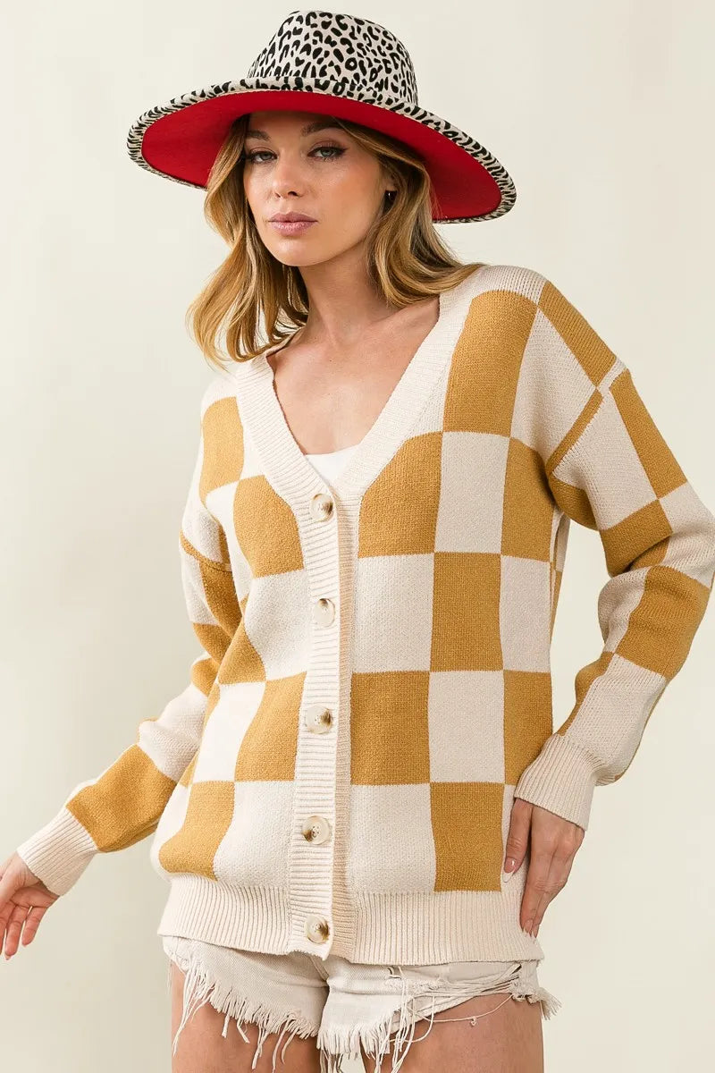 Woman wearing a checkered cardigan and leopard print hat on a plain background