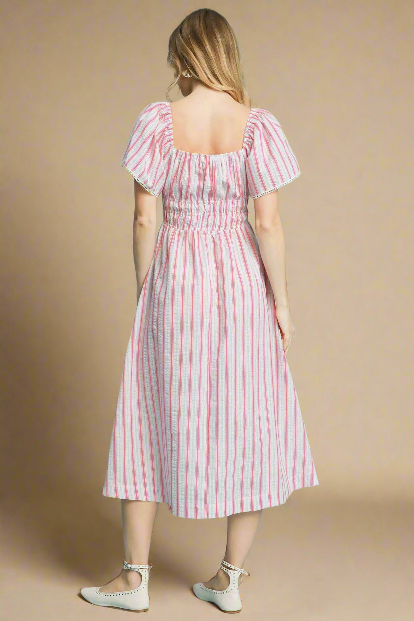 Woman wearing a pink and blue striped dress on a beige background