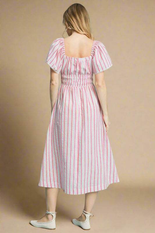 Woman wearing a pink and blue striped dress on a beige background