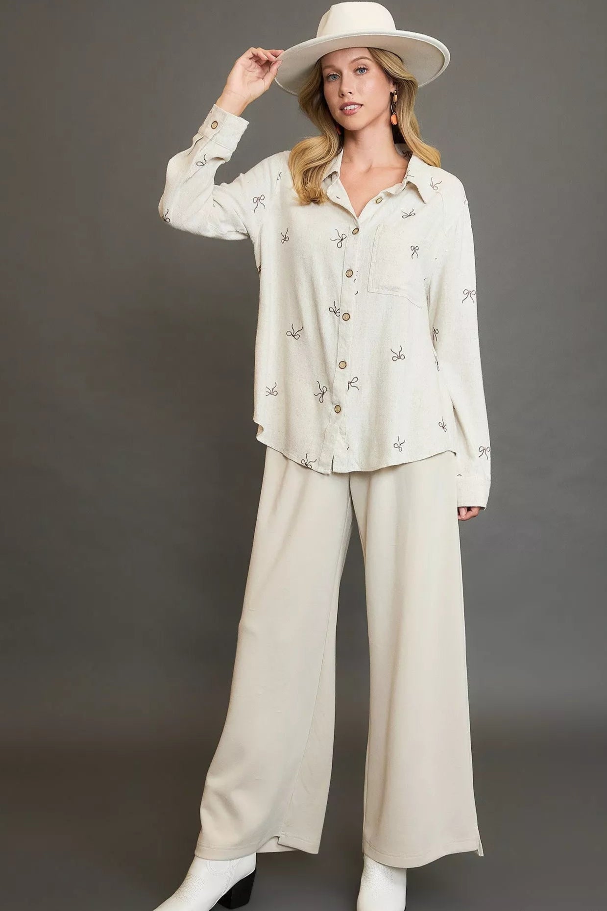 Woman wearing a white outfit with a hat against a gray background