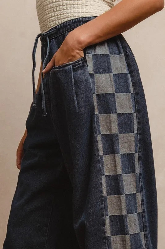 Person wearing dark blue denim jeans with a checkered pattern on a beige background