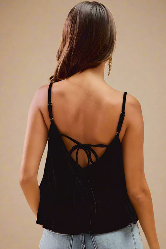 Woman wearing a black strappy top with a beige background