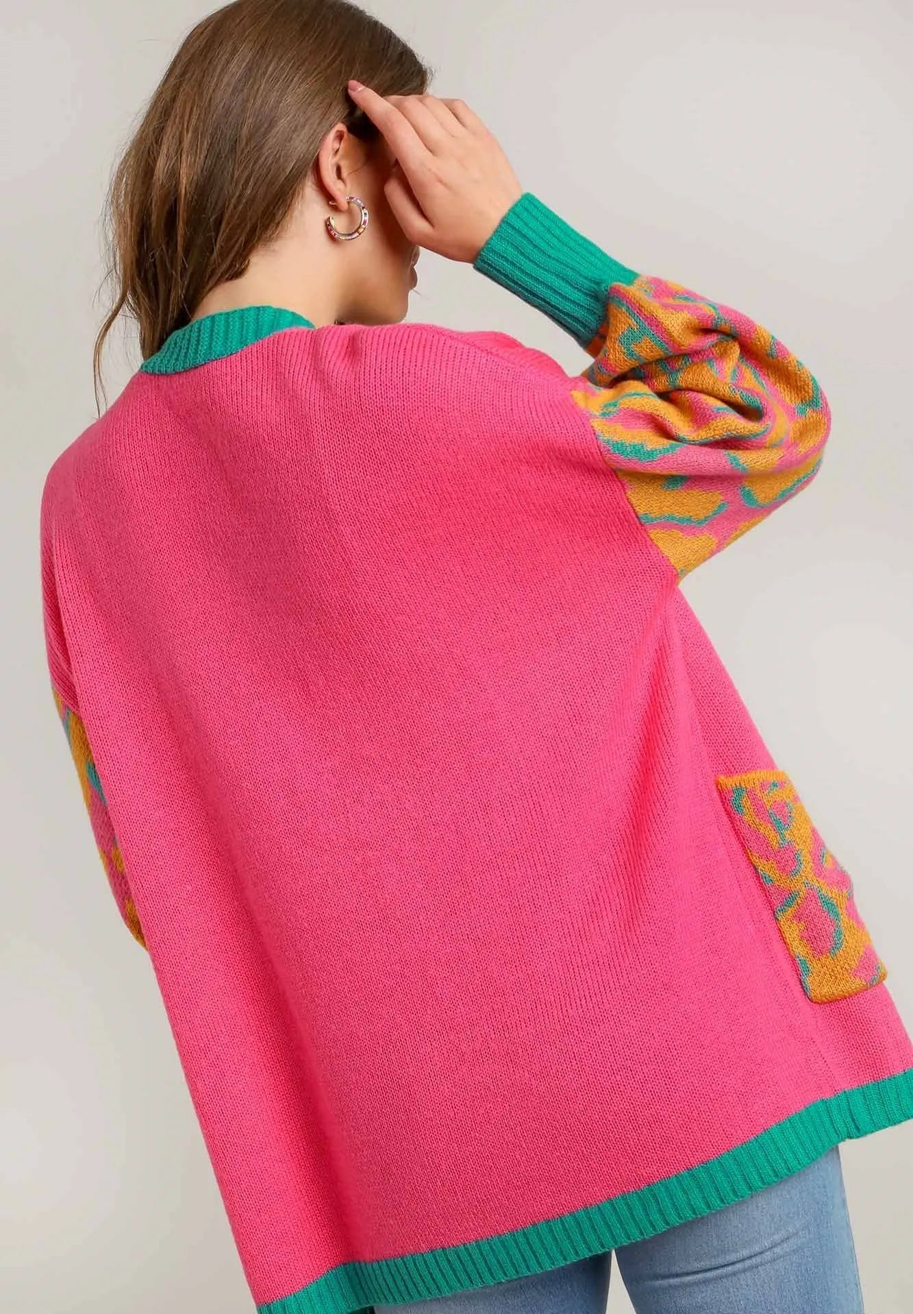 Person wearing a pink cardigan with colorful sleeves against a plain background