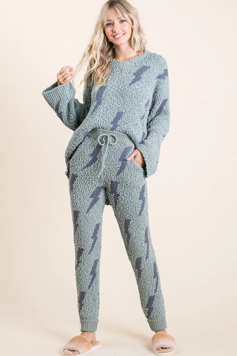 Woman wearing a textured blue loungewear set with feather pattern on a beige background