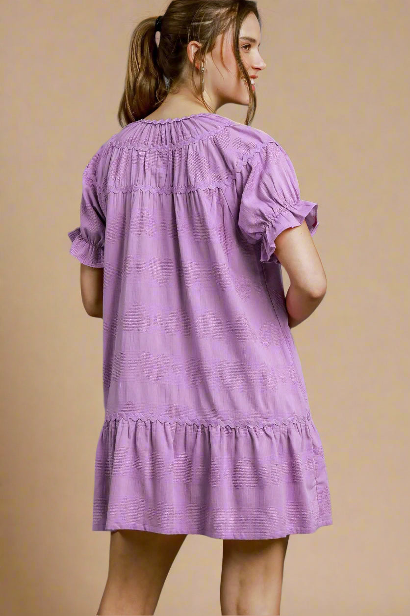 Woman wearing a lavender dress against a beige background